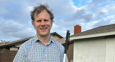 John, an NFB member, smiles outside.